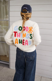 Pull doux et chaud porté par une femme, vue de dos, lettres colorées, jean foncé