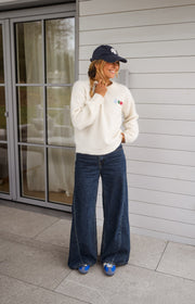 Pull doux et chaud porté par une femme, vue de face, casquette marine, baskets bleues