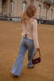 Pull dos ouvert détails dorés porté par une femme, vue de dos, esplanade, jean large