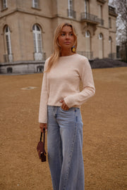 Pull dos ouvert détails dorés porté par une femme, vue de face, esplanade, main au col