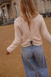 Pull dos ouvert détails dorés porté par une femme, vue de dos ouvert, jean clair