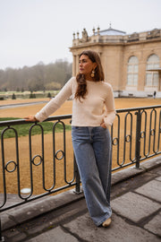 Pull dos ouvert détails dorés porté par une femme, vue de face, rambarde, manches longues