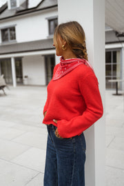 Pull court à dos ouvert porté par une femme, vue de trois-quarts, bandana rouge, jean large