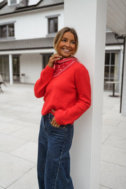 Pull court à dos ouvert porté par une femme, vue de trois-quarts, poteau, sourire