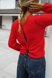 Pull court à dos ouvert porté par une femme, vue de dos, main sur la tête, dos ouvert