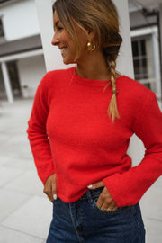 Pull court à dos ouvert porté par une femme, vue rapprochée, tresse, mains sur les hanches
