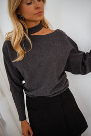 Pull à épaule dénudée gris porté par une femme, vue rapprochée, épaule dénudée, cheveux blonds