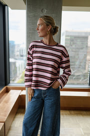 Pull rayé coupe ample porté par une femme, silhouette entière, main dans la poche, près d'un pilier