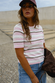 Pull en maille légère porté par une femme, vue rapprochée, casquette, veste marron sur le bras