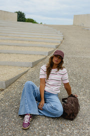 Pull en maille légère porté par une femme, assise, sur le sol, casquette, sac marron