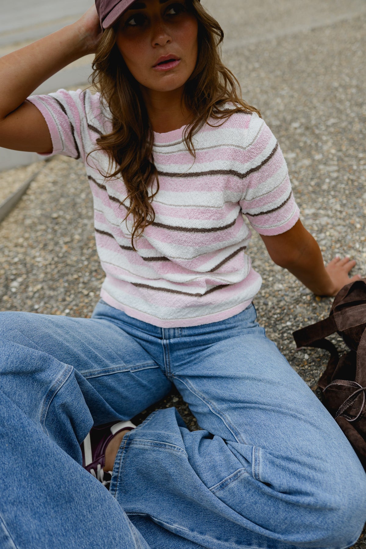 Pull en maille légère porté par une femme, assise, sur le sol, vue rapprochée