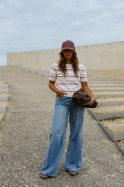 Pull en maille légère porté par une femme, silhouette entière, casquette, sur des gradins