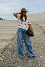 Pull en maille légère porté par une femme, silhouette entière, casquette, main sur la tête