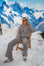 Pull doux à lien noué gris porté par une femme, assise, assise sur une chaise en bois