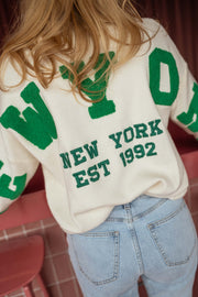 Pull loose à logo dos écru porté par une femme, vue rapprochée, inscription, jean