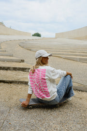 Pull ample à inscriptions porté par une femme, assise, sur le sol, motif rose dans le dos