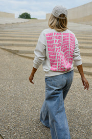 Pull ample à inscriptions porté par une femme, vue de dos, motif rose dans le dos
