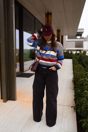 Pull rayé à col rond porté par une femme, vue de face, casquette bordeaux, terrasse