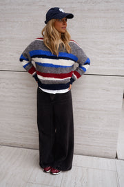Pull rayé à col rond porté par une femme, vue de face, casquette marine, rayures colorées