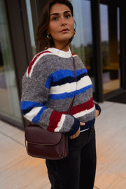 Pull rayé à col rond porté par une femme, vue rapprochée, rayures bleues et rouges, sac bordeaux