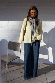 Pull col rond légèrement ample porté par une femme, vue de face, foulard gris, chaise grise