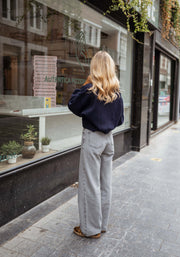 Pull court à col zippé bleu porté par une femme, vue de dos, rue, jean