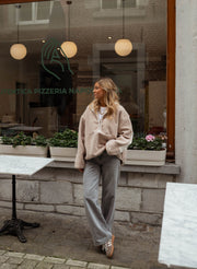 Pull ample à capuche zippé beige porté par une femme, silhouette entière, vitrine, lumières