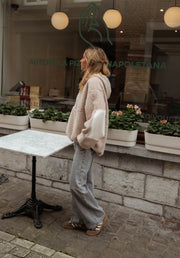 Pull ample à capuche zippé beige porté par une femme, vue de dos, vitrine, capuche