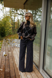 Pull jacquard col montant porté par une femme, vue de face, terrasse en bois, pantalon noir