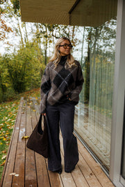 Pull jacquard col montant porté par une femme, vue de face, terrasse en bois, sac noir