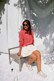 Pull délavé col boutonné porté par une femme, assise, sur une chaise, baskets blanches