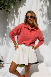 Pull délavé col boutonné porté par une femme, silhouette entière, jupe blanche, lunettes de soleil