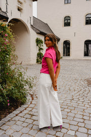 Pull à manches courtes noué porté par une femme, vue de dos, pantalon blanc