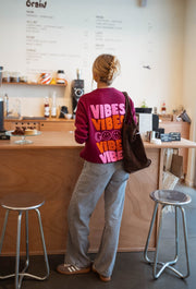 Pull à logo au dos bordeaux porté par une femme, vue de dos, logo VIBES, comptoir