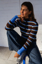 Pull rayé moulant boutonné porté par une femme, assise, tabouret bleu, jambe repliée