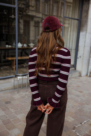 Pull moulant rayé à volants bordeaux et blanc porté par une femme, vue de dos, casquette