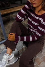 Pull moulant rayé à volants bordeaux et blanc porté par une femme, assise, vue rapprochée