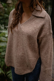 Pull doux col V loose beige porté par une femme, vue rapprochée, col V, cheveux bruns