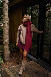 Pull doux col V loose beige porté par une femme, vue de face, écharpe bordeaux, bottines