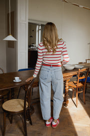 Pull rayé à col bateau porté par une femme, vue de dos, chaussures rouges, jean clair