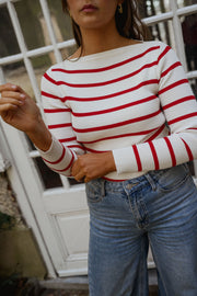 Pull rayé à col bateau porté par une femme, vue rapprochée, rayures rouges et blanches, jean clair