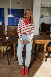 Pull rayé à col bateau porté par une femme, silhouette entière, foulard rouge, chaussures rouges