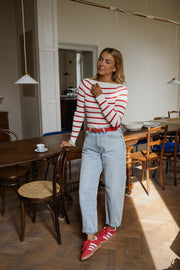 Pull rayé à col bateau porté par une femme, silhouette entière, chaussures rouges, jean clair