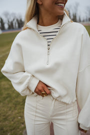 Pull court à cordons écru porté par une femme, vue rapprochée, main dans la poche, t-shirt rayé