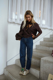 Pull doux à manches longues marron porté par une femme, vue de trois-quarts, escalier, baskets