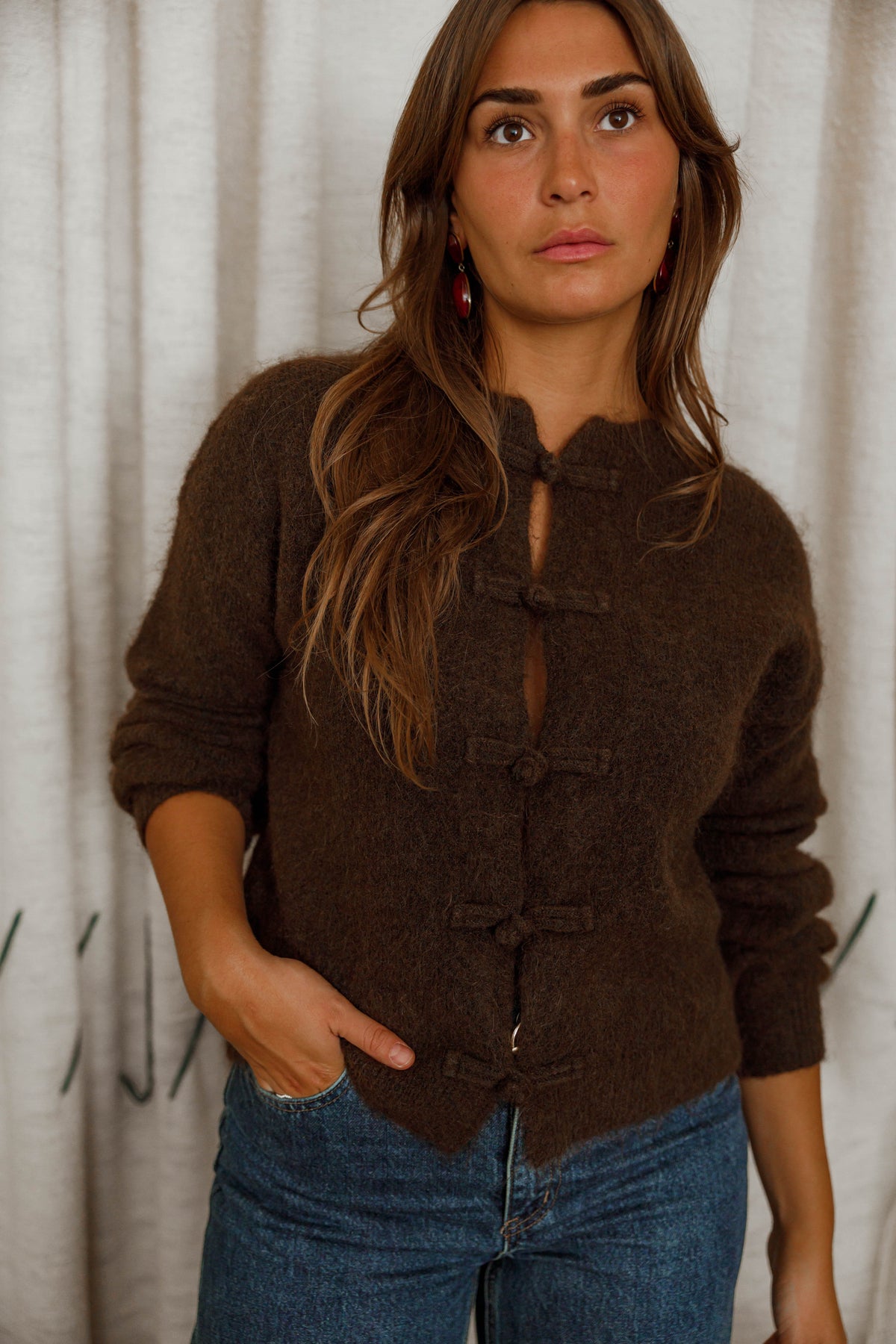 Pull doux à boutonnage mandarin marron foncé porté par une femme, vue de face