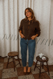 Pull doux à boutonnage mandarin marron foncé porté par une femme, silhouette entière, mains dans les poches