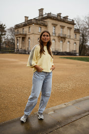 Pull à bandes sur manches porté par une femme, vue de face, manoir, allée