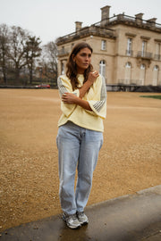 Pull à bandes sur manches porté par une femme, vue de face, manoir, jean bleu