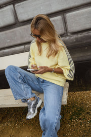 Pull à bandes sur manches porté par une femme, assise, banc, lunettes